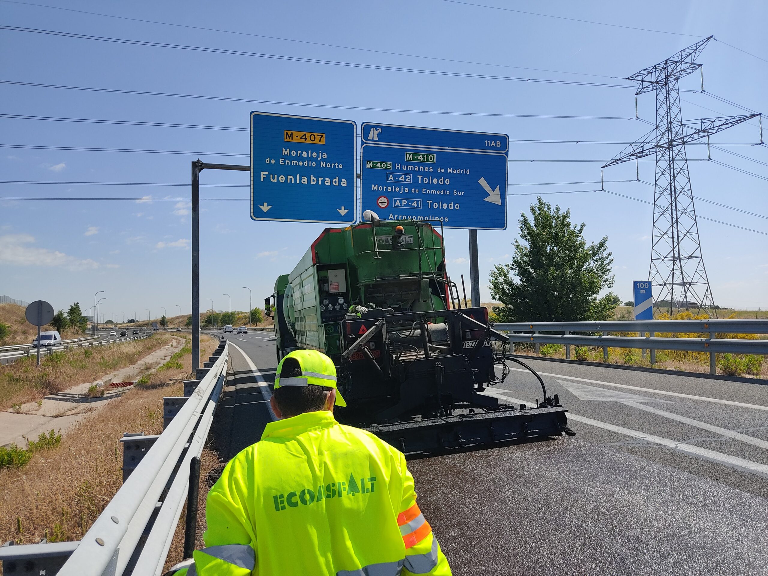 Vehículo de Ecoasfalt en la carretera con un operario utilizando señalización para dirigir el tráfico de manera segura