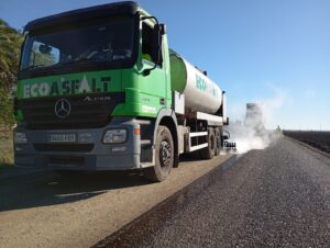 Maquinaria aplicando doble tratamiento superficial con emulsión bituminosa en camino rural de Los Palacios y Villafranca