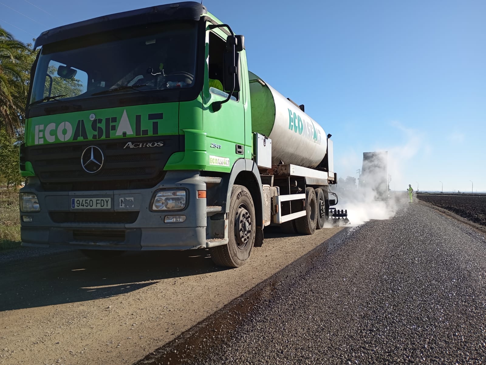 Maquinaria aplicando doble tratamiento superficial con emulsión bituminosa en camino rural de Los Palacios y Villafranca
